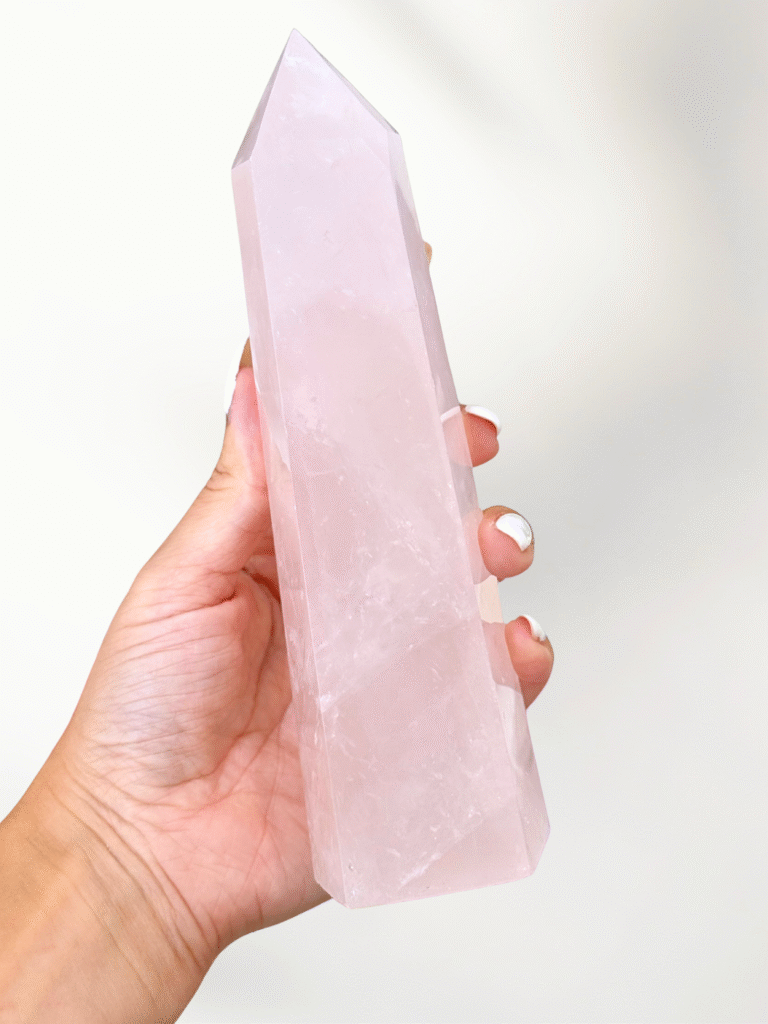 Large polished pink rose quartz crystal tower, hand selected for heart chakra and self love practice, on bone background.
