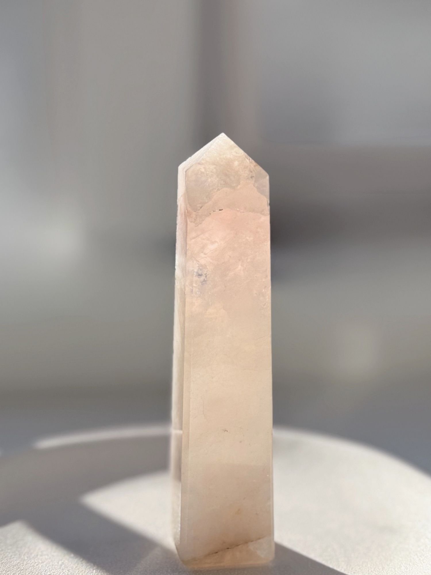 Rose Quartz Tower 1 small polished pink rose quartz crystal tower from madagascar, hand selected for heart chakra altar work, on bone background.