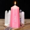 Love crystal candle with rough rose quartz pieces, unscented paraffin, on bone background with botanical sprig.