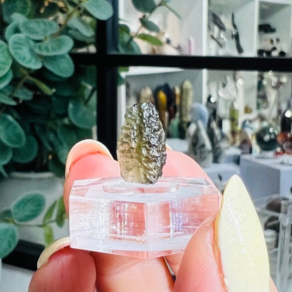 Raw moldavite for sale 0.60g Czech tektite B6, grey green natural glass on a clear hexagonal display base, Mystic Grove UK