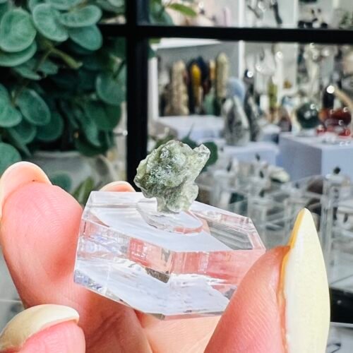 Home 2026 20 Natural Czech moldavite 0.52g raw tektite C3, pale sage green natural glass on a clear hexagonal display base, Mystic Grove UK