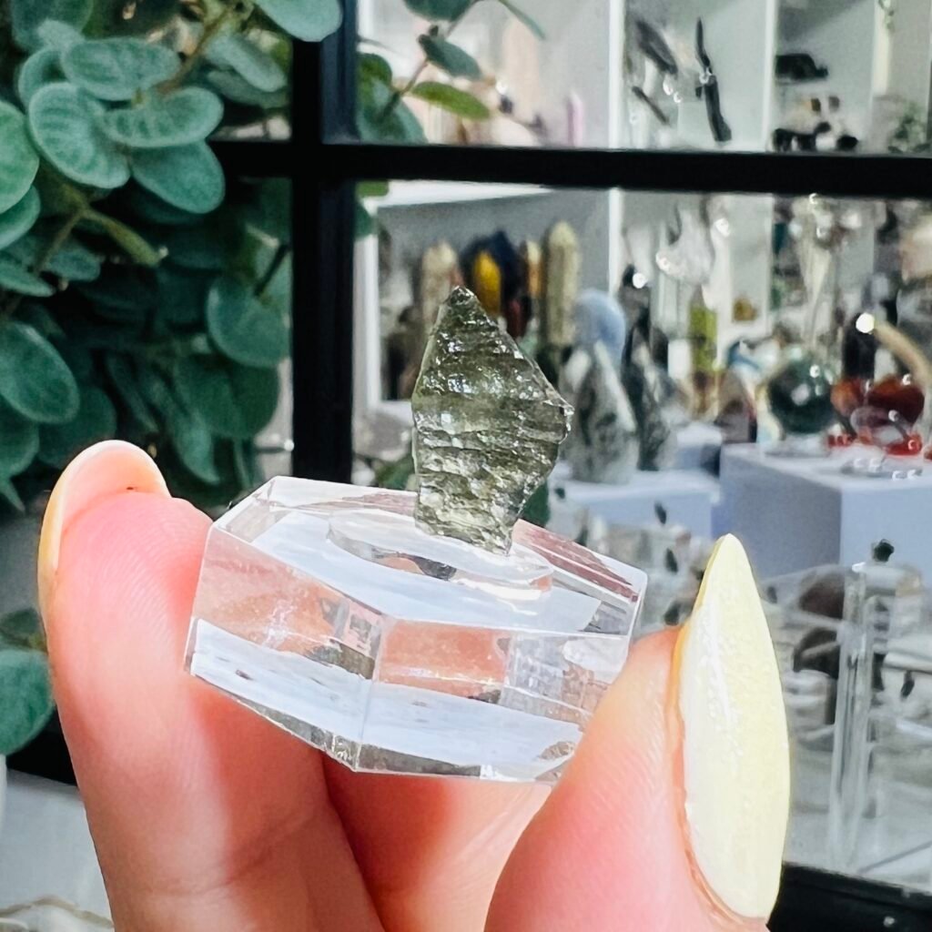 Raw moldavite piece 0.54g Czech tektite C4, olive green natural glass on a clear hexagonal display base, Mystic Grove UK