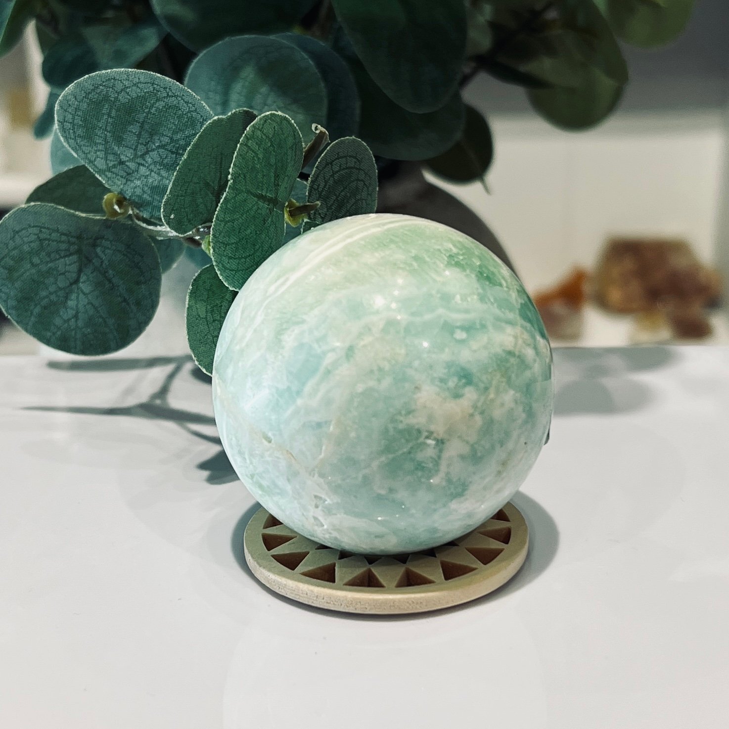 Hemimorphite Sphere 60mm 281g 3 Green hemimorphite sphere on its wooden sphere stand showing the sweeping band across one face