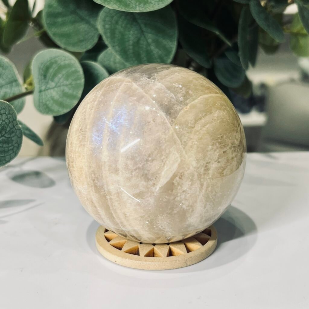 Blue flash moonstone sphere 70mm on a wooden sphere stand, cream to pale peach body, Mystic Grove UK