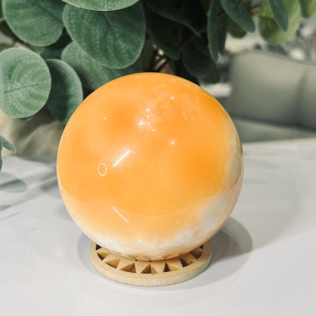 Orange calcite sphere 70mm on a wooden sphere stand, tangerine with cream clouds, Mystic Grove UK