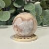 Flower Agate Sphere 49mm Flower agate sphere 49mm on a wooden stand, peach pink with white blossom patterns, Mystic Grove UK