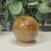 Golden Healer Quartz Sphere 63mm 1 Golden healer quartz sphere 63mm on wooden stand, view 1