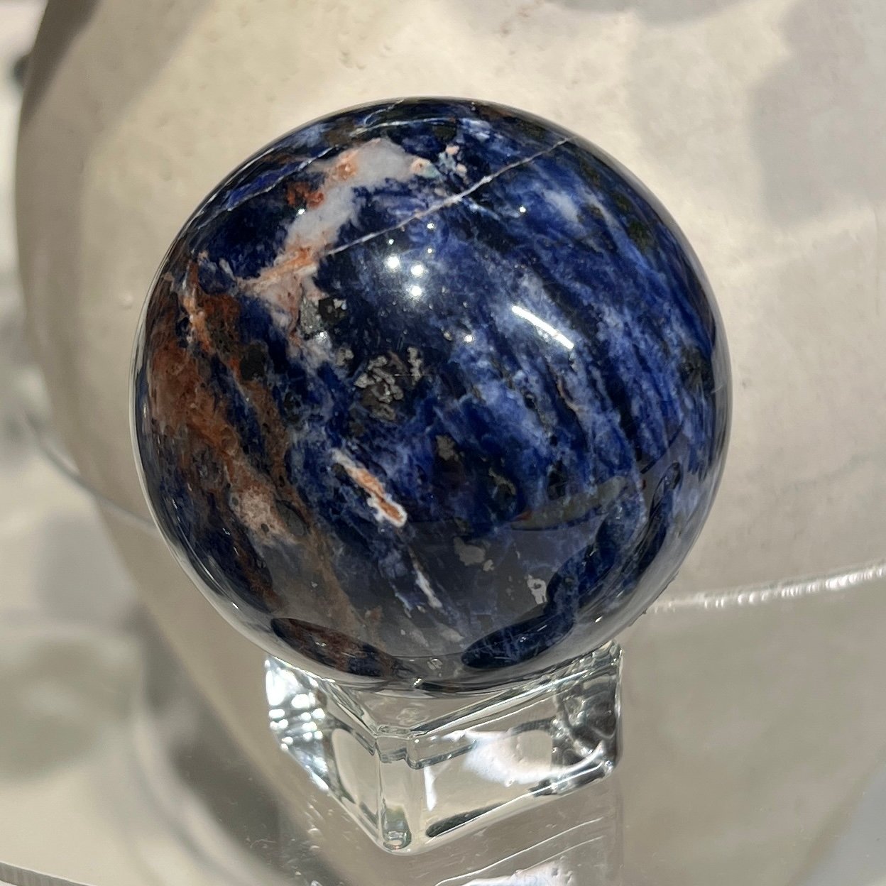 Sodalite sphere A 55mm, deep blue with rust and orange bands Sodalite sphere A 55mm, deep blue with rust and orange bands