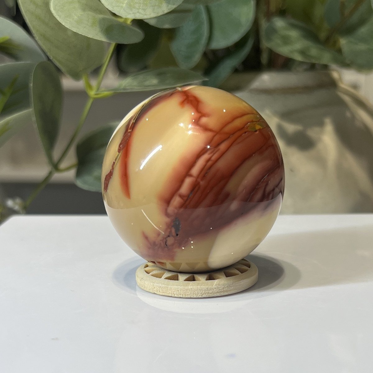 Mookaite Sphere C Red and cream mookaite sphere on a wooden stand