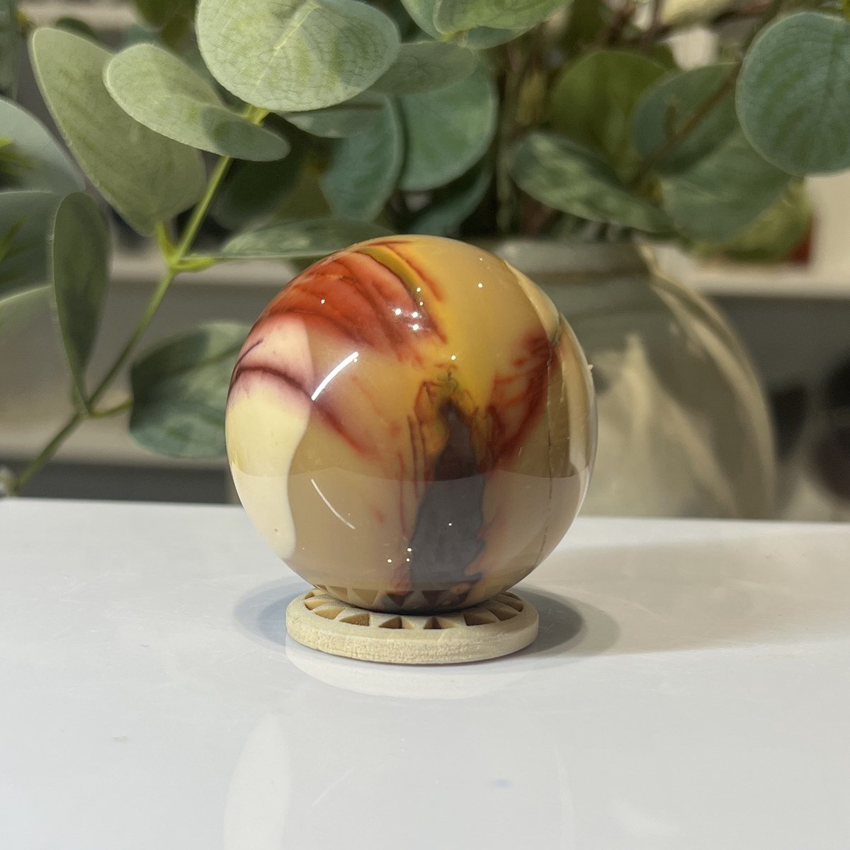 Mookaite Sphere C Red and cream mookaite sphere on a wooden stand