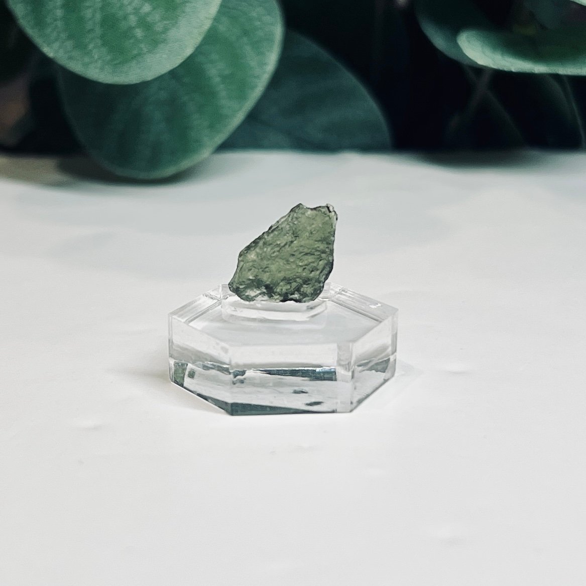 Raw moldavite A5 0.69g Czech tektite from the Chlum sand mine on a clear stand