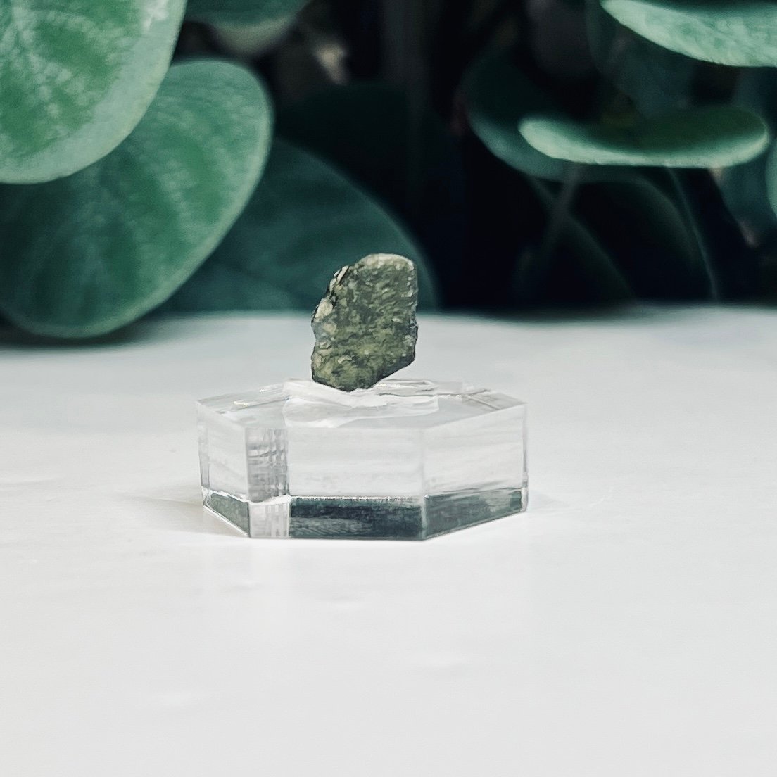 Raw moldavite B2 0.52g Czech tektite from the Chlum sand mine on a clear stand