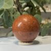 Red jasper sphere A Red jasper sphere A, 63mm, brick red with dark speckles, on a wooden stand