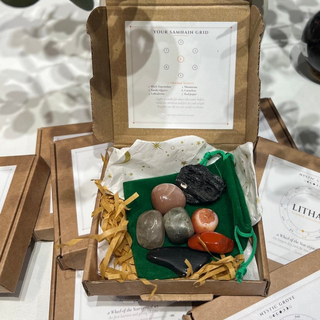 Home 2026 59 Samhain Wheel of the Year crystal set, open box with seven tumblestones on a green pouch and the Samhain grid card